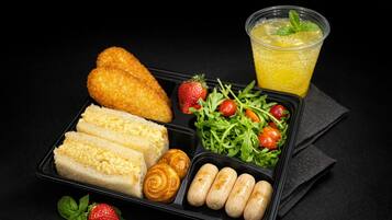 Eine Serviettafel mit Brot, Croissants, Würstchen, einem Salat, Erdbeeren und einem Getränk.