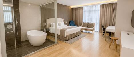 Una habitación de hotel moderna con una bañera grande, una cama, un sofá, un escritorio y un televisor.