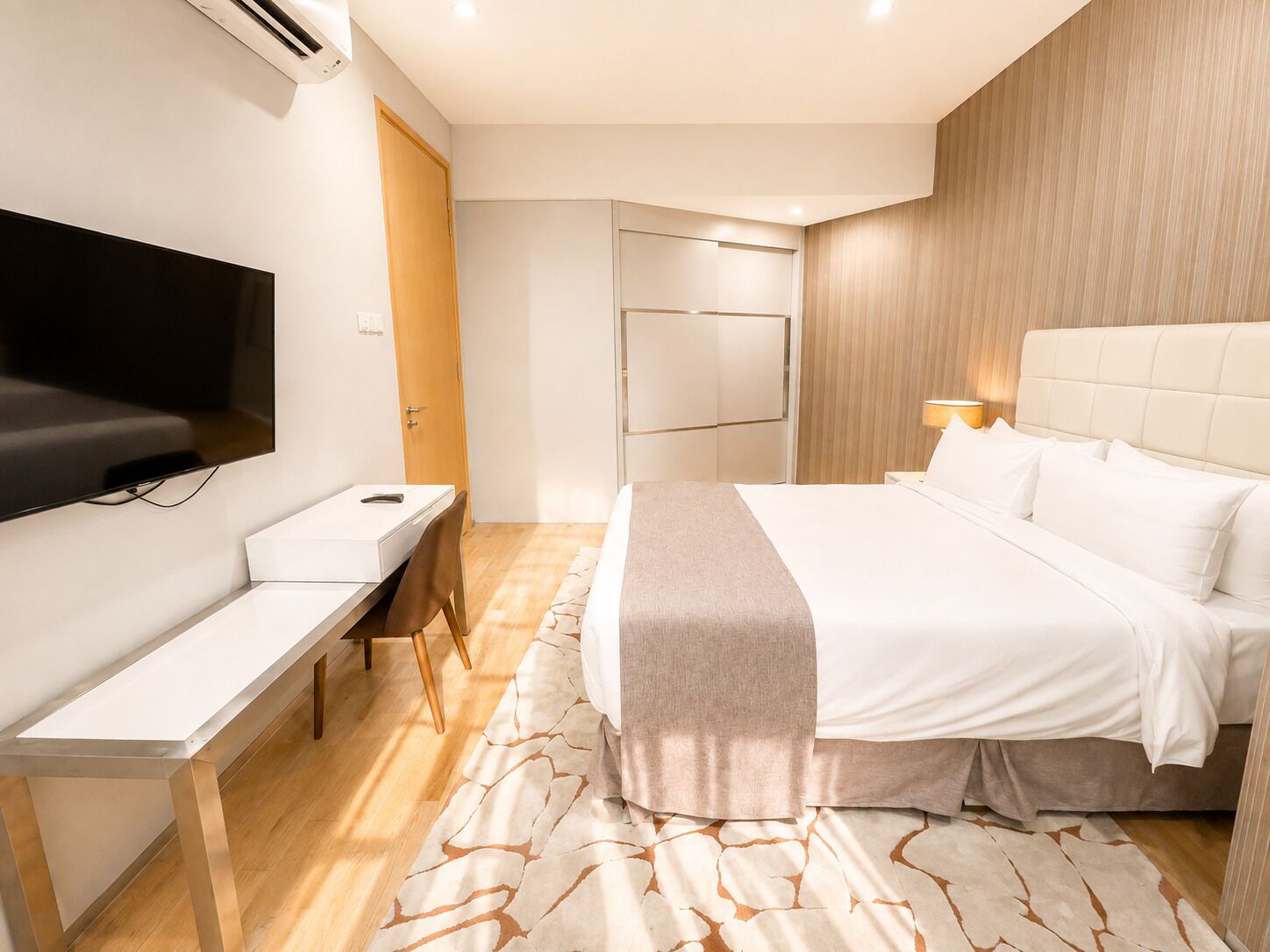 Habitación de hotel con cama, mesita de noche, televisor y escritorio.