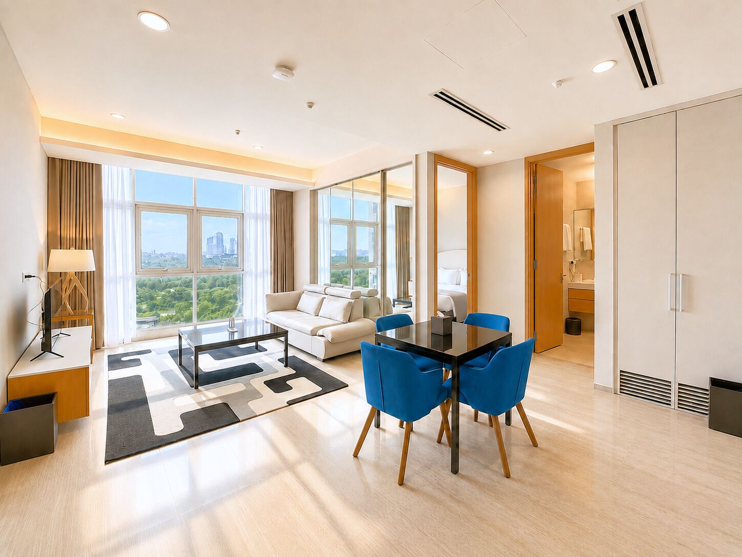 Une chambre d’hôtel moderne dotée d’un coin repas, d’un canapé, d’une table basse et offrant une vue sur le paysage urbain.