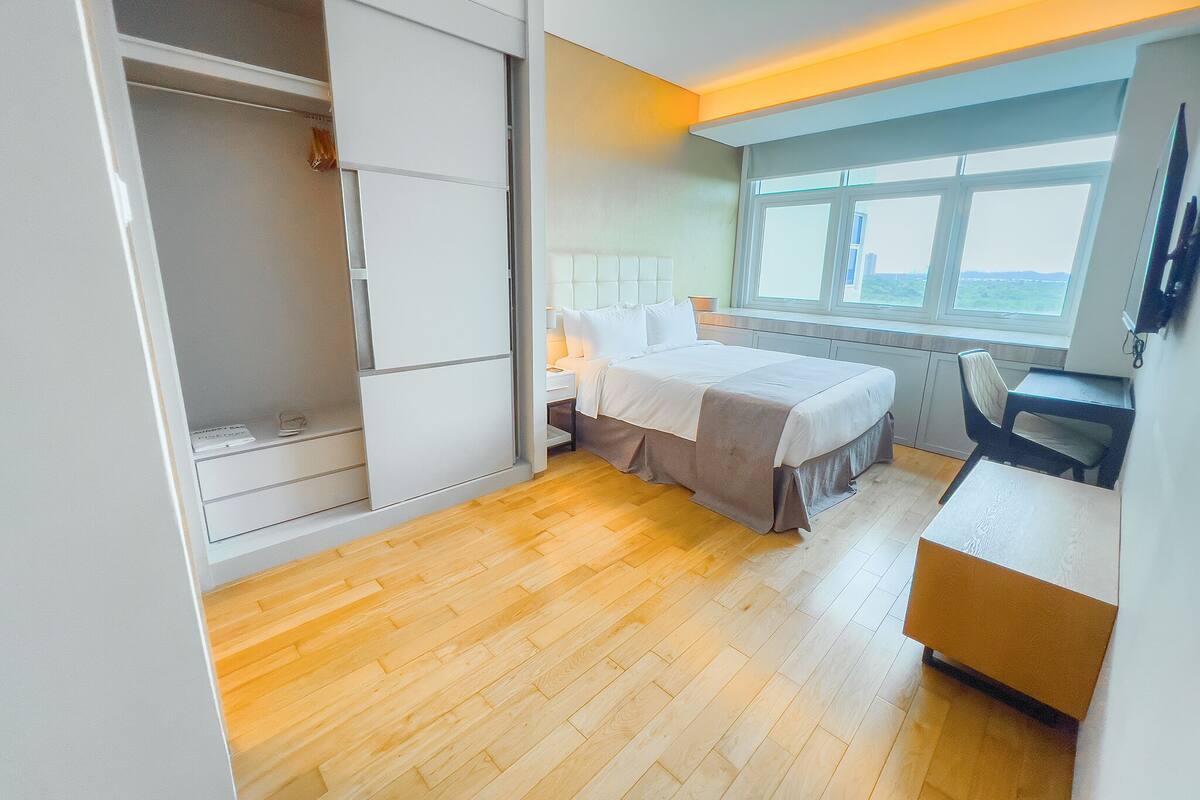 A modern bedroom with a bed, a desk, and a wardrobe.