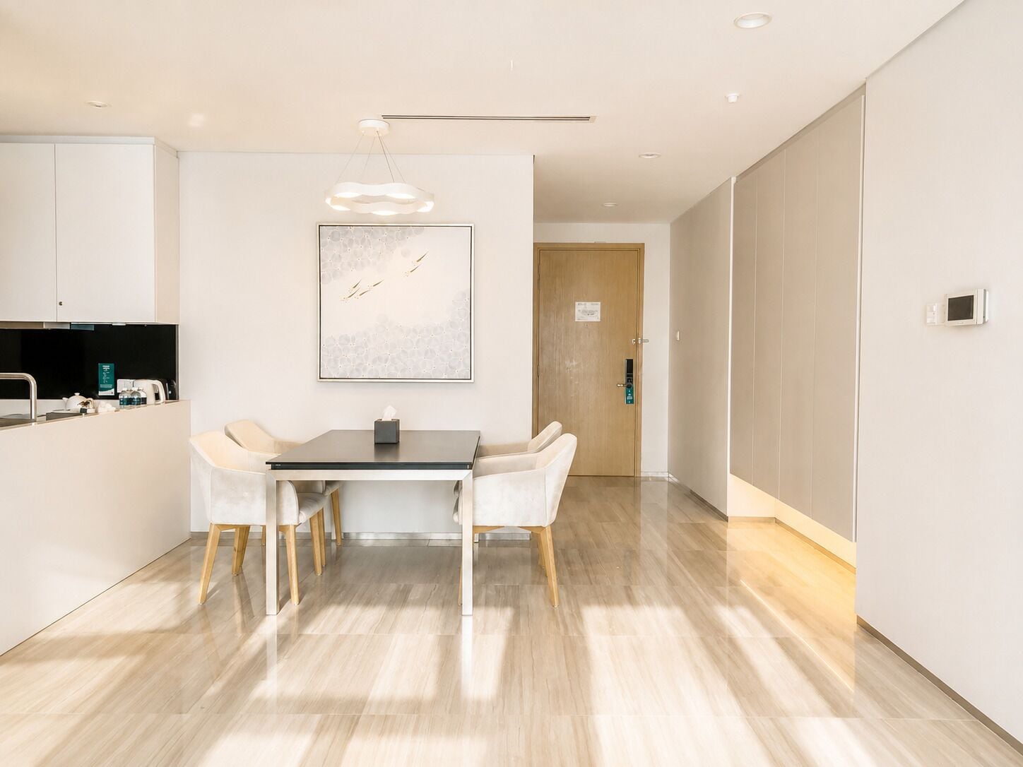 A modern kitchen with a dining area, a wooden door, and a light fixture.