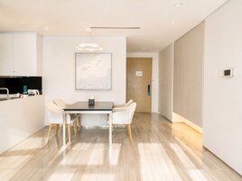 A modern kitchen with a dining area, a wooden door, and a light fixture.