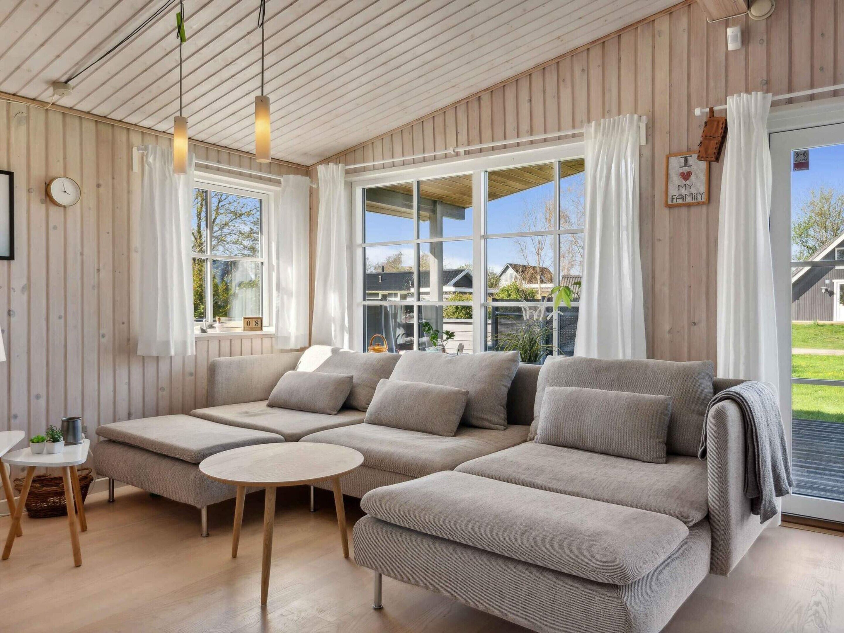 A modern living room with a sectional sofa, a round coffee table, and large windows offering a view of the outside.
