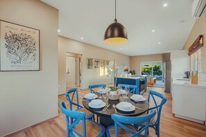 A modern kitchen with a central island, a dining area with blue chairs, and a hanging pendant light.