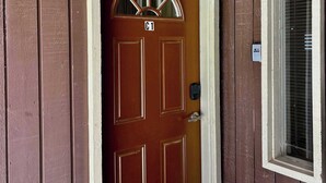 A brown wooden door with a white frame, a number plate 'C1', and a doorbell.