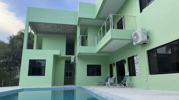 A modern building with a swimming pool, balconies, and air conditioning units.