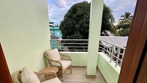 A balcony with wicker furniture and a view of the sky and trees. - MeMe’s Place – Parrot (Placencia)