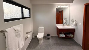 A modern bathroom with a toilet, sink, and window. - MeMe’s Place – Parrot (Placencia)