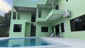 A modern building with a swimming pool, balconies, and air conditioning units.