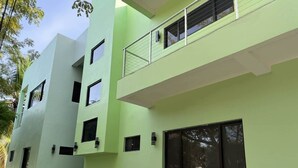 A multi-story building with balconies, windows, and a flat roof. - MeMe’s Place – Toucan (Placencia)