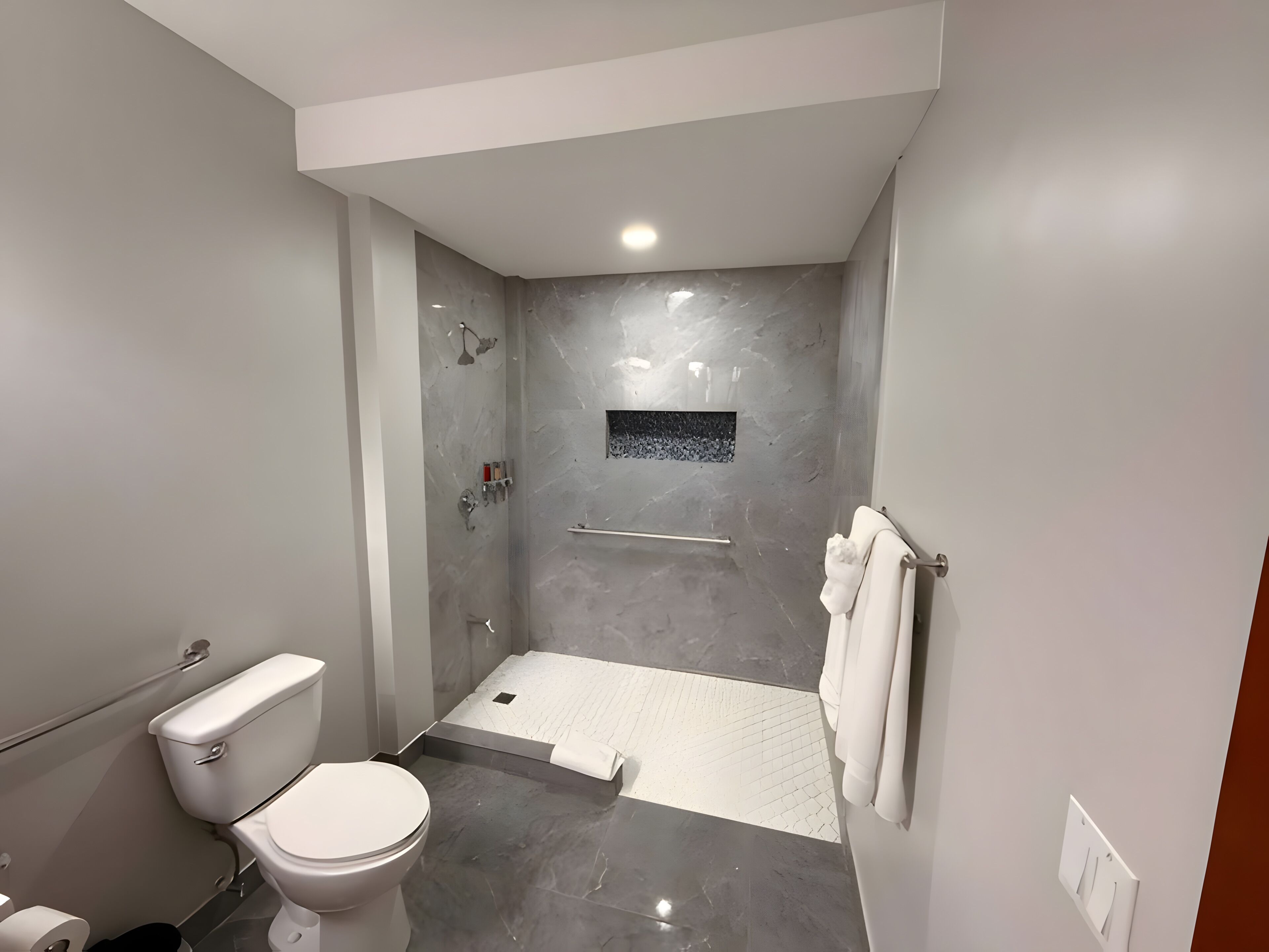 A modern bathroom with a toilet, shower, and a towel rack.