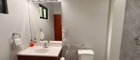 A bathroom with a vanity, sink, mirror, towel rack, toilet, and shower.
