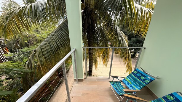 A balcony with a view of a sandy beach, surrounded by palm trees.