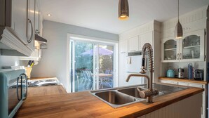 Una cucina moderna con piano di lavoro in legno, lavello in acciaio inossidabile e mobili bianchi.