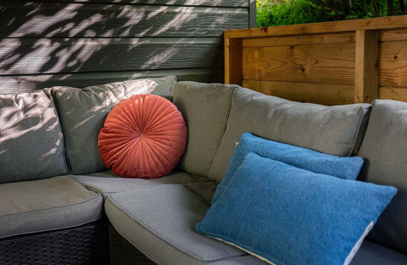 Um sofá modular com almofadas cinzas e um travesseiro vermelho e azul.