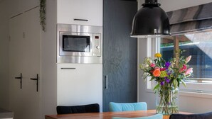 Une cuisine moderne équipée d’appareils électroménagers en acier inoxydable, une table à manger en bois et un vase rempli de fleurs.