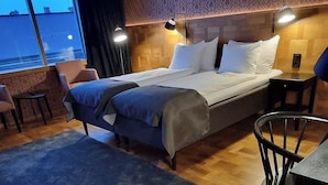 Een hotelkamer met een bed, een bureau, een stoel en uitzicht op zee.