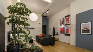 Ein modernes Wohnzimmer mit einer schwarzen Couch, einem Couchtisch und einer Topfpflanze.