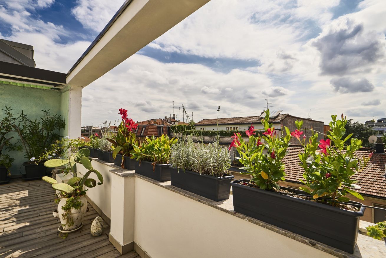 A rooftop terrace with potted plants and a view of the cityscape.