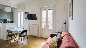 A compact living space with a kitchenette, a dining area, a sofa, and a TV mounted on the wall. - Bright Urban Terrace | Porta Romana (Milan)
