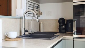 A modern kitchen with a double sink, a coffee maker, and a kettle. - Bright Urban Terrace | Porta Romana (Milan)