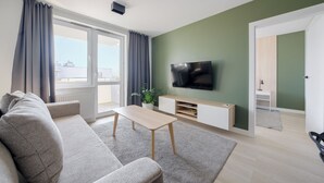 Een moderne woonkamer met een bank, salontafel en televisie op een witte kast.
