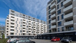 Een meerlaags woongebouw met een parkeerplaats ervoor.