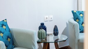 En stue med to lyseblå sofaer, et glastæppe og et maleri med sejlbåde på væggen.