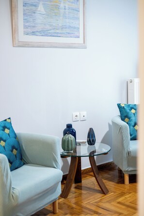 A living room with two light blue sofas, a glass coffee table, and a painting of sailboats on the wall. - Central Apartment with Acropolis View by Meros (Athina)