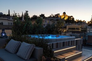 A rooftop terrace with a hot tub, outdoor seating, and a view of a cityscape at dusk. - Central Apartment with Acropolis View by Meros (Athina)