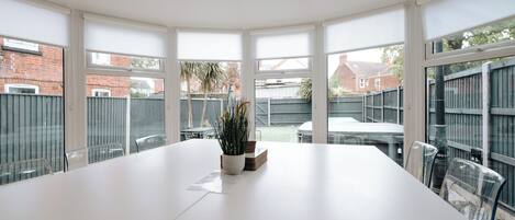 A large, white conference table with chairs, a potted plant, and a menu on the table.