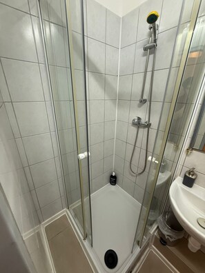 Eenvoudig appartement | Badkamer | Een douche, gratis toiletartikelen, een haardroger, handdoeken