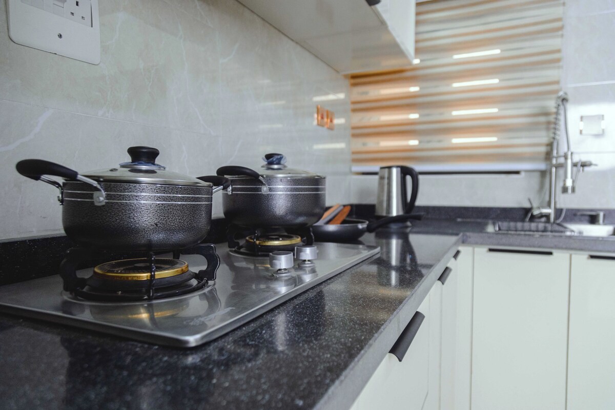 A kitchen with two gas stoves, a kettle, and a coffee maker on the counter.