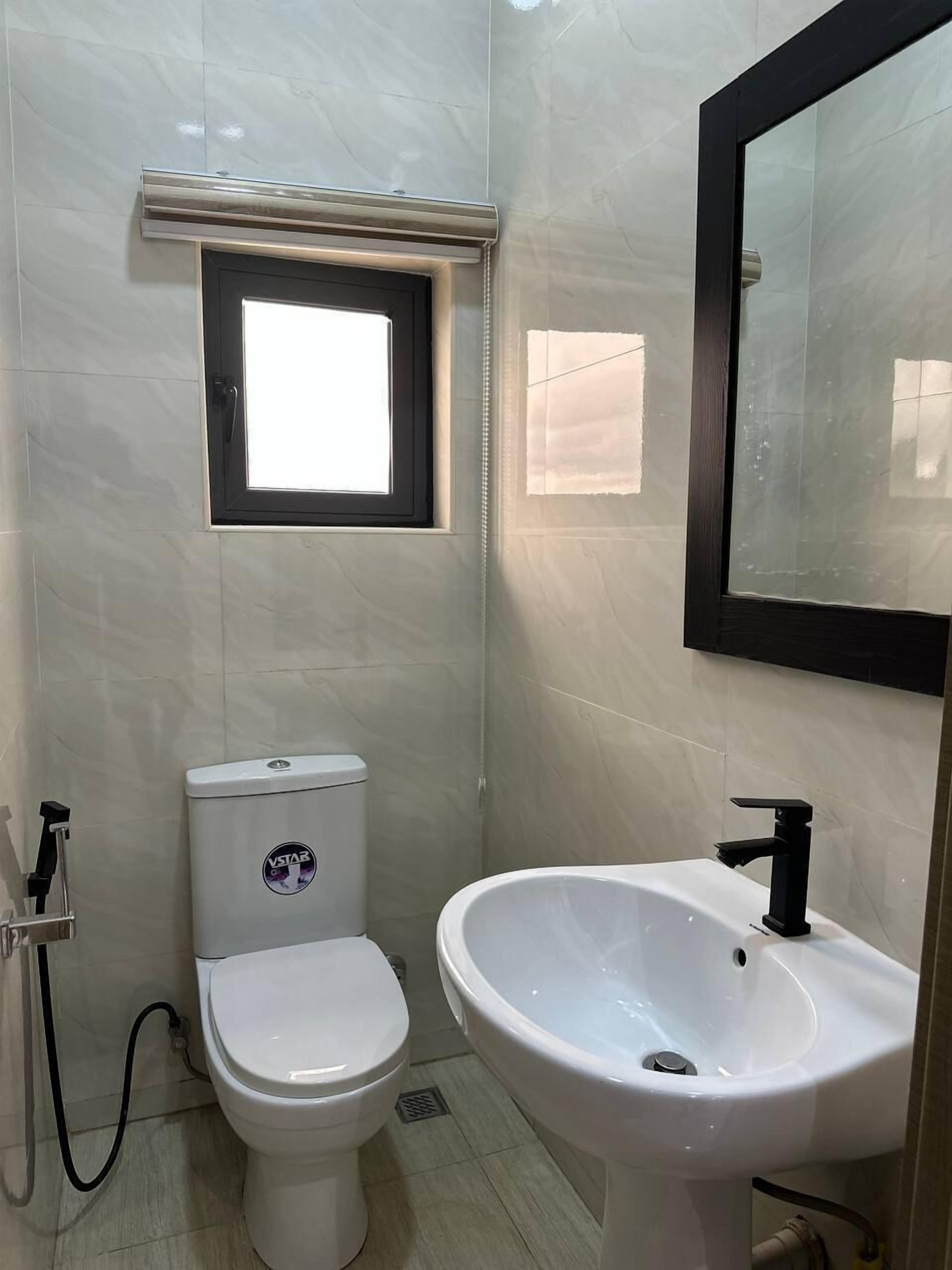 Un baño con inodoro, lavamanos y ventana.
