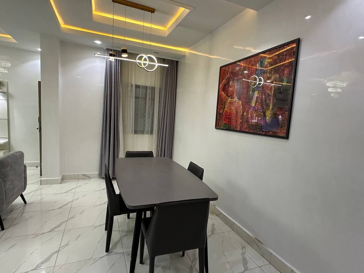 Een moderne vergaderruimte met een marmeren vloer, een lange tafel met stoelen, een groot abstract schilderij aan de muur en een plafond met inbouwverlichting.