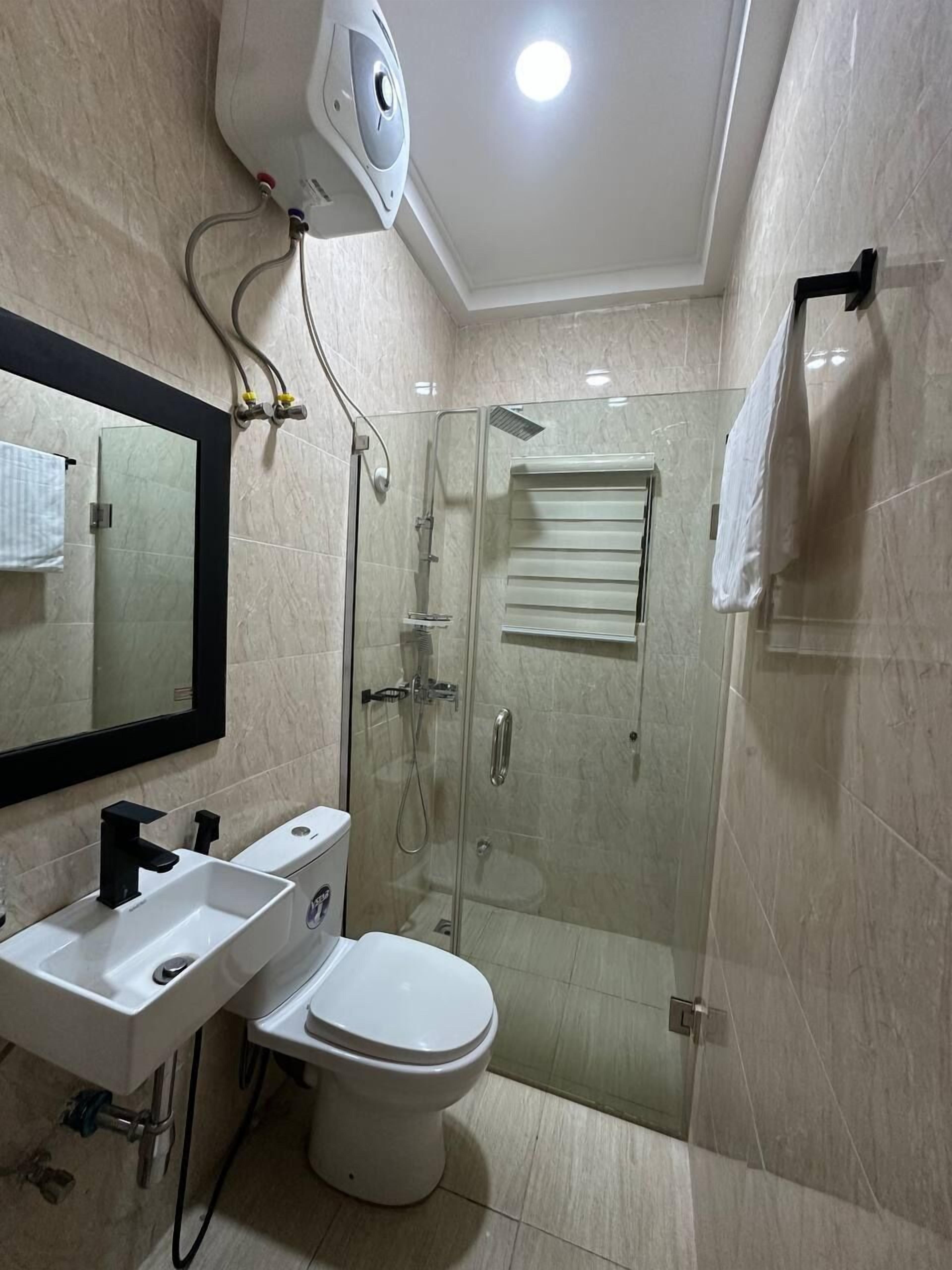 A modern bathroom with a glass-enclosed shower, a white sink, and a toilet.