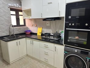 Een koelkast, een magnetron, een oven, kookgerei, borden en bestek