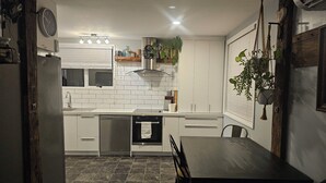 A modern kitchen with white cabinets, a built-in oven, and a dining area with a dark wooden table and chairs.