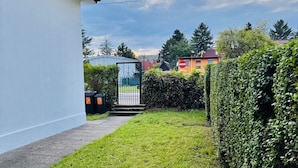 Un quartier résidentiel avec un chemin menant à une entrée fermée par un portail, entouré de verdure et de maisons.