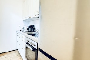 A compact kitchen with white cabinets, a sink, a coffee maker, and a microwave.