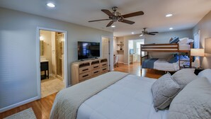 A bedroom with a bed, a TV, a ceiling fan, a desk, and a bunk bed. - TuscaLodge: Close to Stadium, Big on Comfort! (Tuscaloosa)