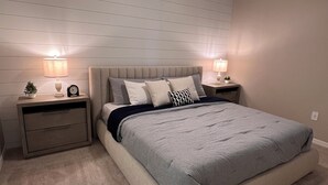 A bedroom with a bed, two bedside tables, a ceiling fan, and a nightstand with a lamp.