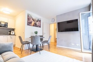 Eine moderne Wohnung mit Essbereich, Küche und großem Fernseher.
