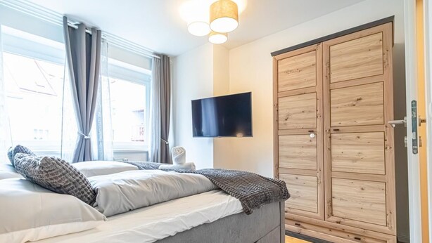 Una camera da letto con un letto, una televisione e un'armadiatura in legno.