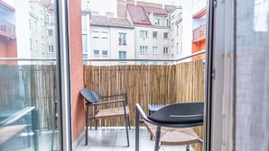 Un balcone con vista su edifici, una recinzione di bambù e due sedie.