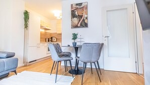 Un soggiorno moderno con un divano, due poltrone, un tavolo da pranzo e una cucina sullo sfondo.