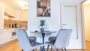 Una cucina moderna con mobili bianchi, un tavolo da pranzo con due sedie e una pianta in vaso.