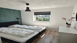 Ein Schlafzimmer mit zwei Betten, einem Fenster mit Blick, einem Schreibtisch und einer Pendelleuchte.