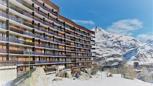 A multi-story hotel with balconies, set against a snowy mountain backdrop. - Apartment in Tignes Le Lac on Ski Slopes (Tignes)